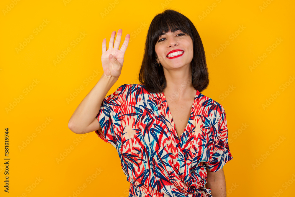 Young woman standing against gray wall showing and pointing up with fingers number four while smiling confident and happy. Young woman standing against gray wall showing and pointing up with fingers number four while smiling confident and happy.