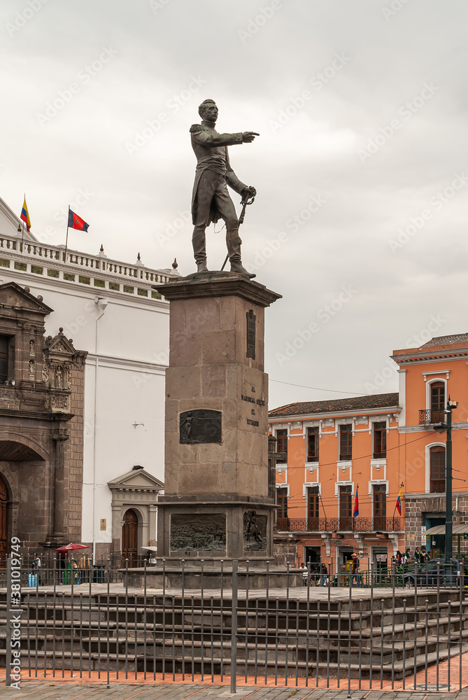 Quito, Ecuador - December 2, 2008: Historic Downtown. Plaza Santo Domingo. Statue of Jose de Sucre on pedestal in front of cathedral. People on square under gray cloudscape.