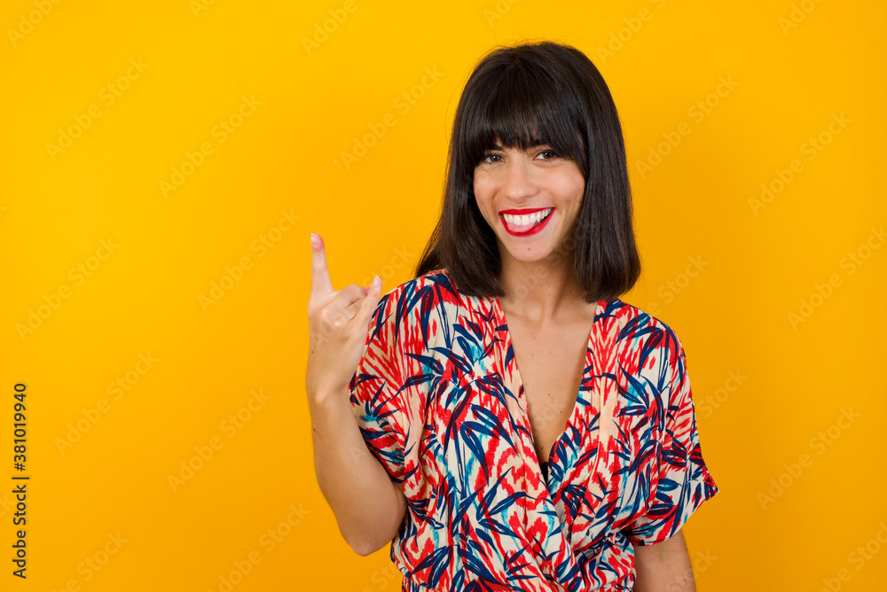 Portrait of a crazy girl showing tongue horns up gesture, expressing excitement of being on concert of band. Portrait of a crazy girl showing tongue horns up gesture, expressing excitement of being on concert of band.