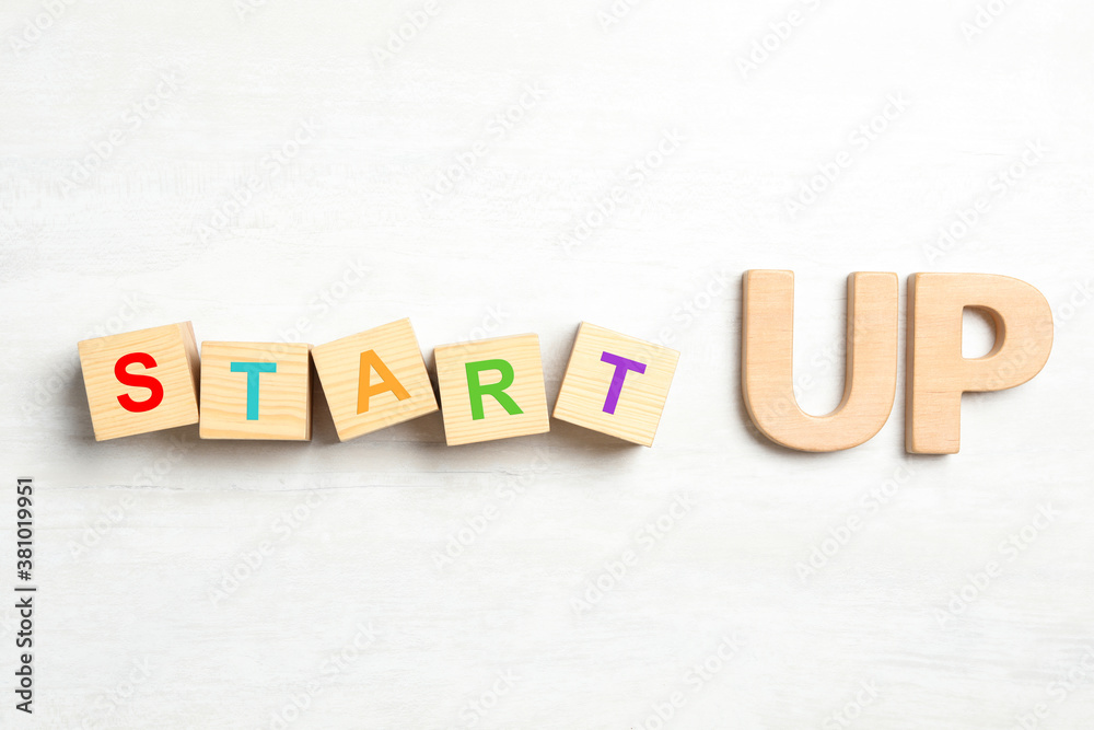 Obraz premium Words START UP made with wooden blocks on white background, flat lay