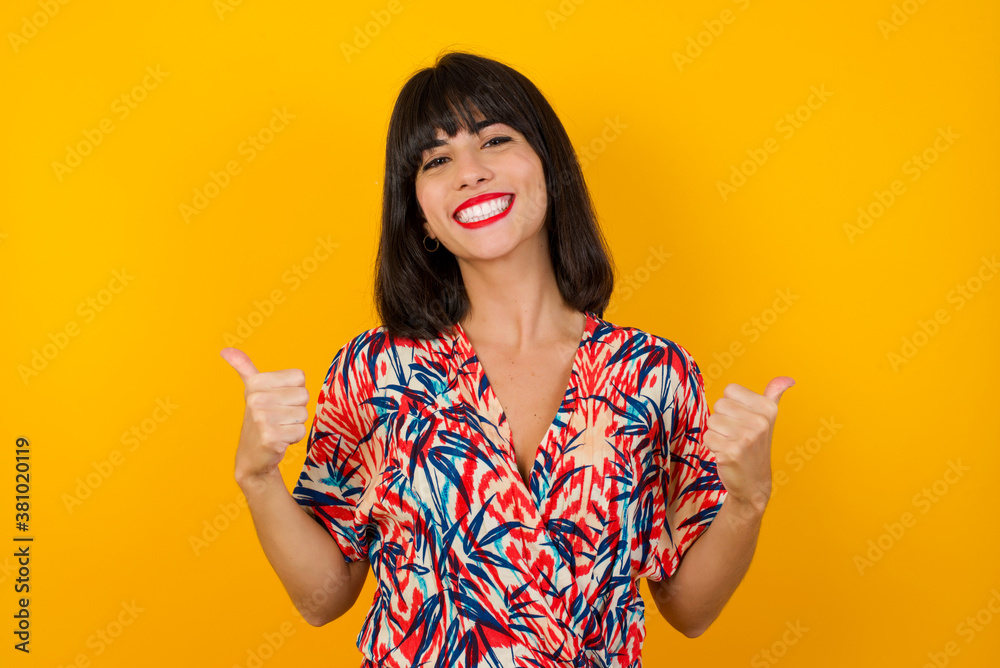 Closeup of young optimistic female isolated on grey background showing thumbs up with positive emotions of content and happiness. Copyspace, concept of satisfaction with quality and recommendation.