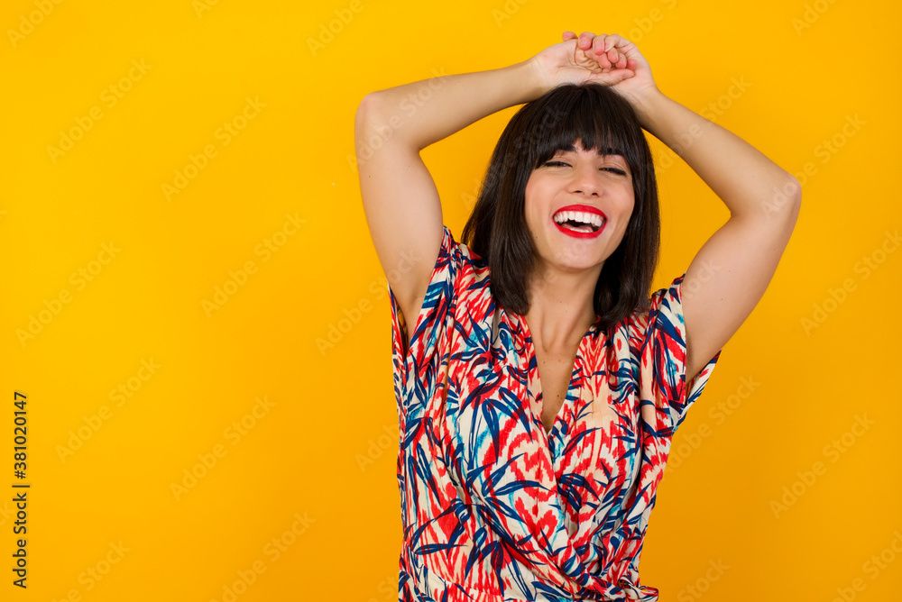 Portrait of beautiful brunette female looks with excitement at camera, keeps hands raised over head notices something unexpected, isolated over gray wall. Lovely woman reacts on sudden news. Portrait of beautiful brunette female looks with excitement at camera, keeps hands raised over head notices something unexpected, isolated over gray wall. Lovely woman reacts on sudden news.