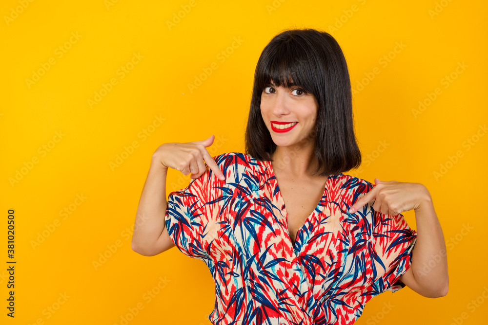 Charming emotive caucasian woman pointing down or at her t-shirt while smiling joyfully and expressing positive emotions over white background. Girl trained a lot, she wants to show her muscles Charming emotive caucasian woman pointing down or at her t-shirt while smiling joyfully and expressing positive emotions over white background. Girl trained a lot, she wants to show her muscles