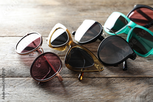 Many different stylish sunglasses on wooden background