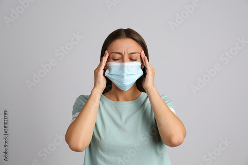 Stressed woman in protective mask on grey background. Mental health problems during COVID-19 pandemic