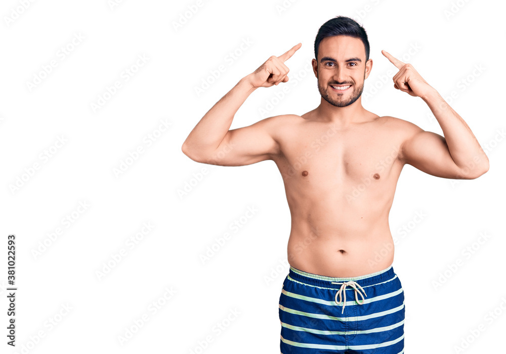 Young handsome man wearing swimwear smiling pointing to head with both hands finger, great idea or thought, good memory