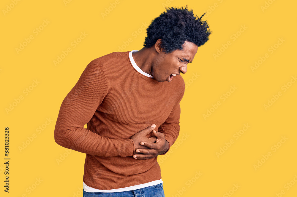 Handsome african american man with afro hair wearing casual clothes with hand on stomach because nausea, painful disease feeling unwell. ache concept. Handsome african american man with afro hair wearing casual clothes with hand on stomach because nausea, painful disease feeling unwell. ache concept.