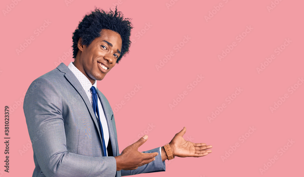 Handsome african american man with afro hair wearing business jacket inviting to enter smiling natural with open hand Handsome african american man with afro hair wearing business jacket inviting to enter smiling natural with open hand