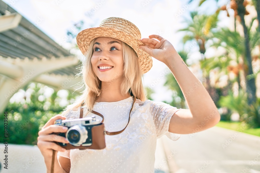 Young caucasian tourist girl smiling happy using vintage camera at street of city.