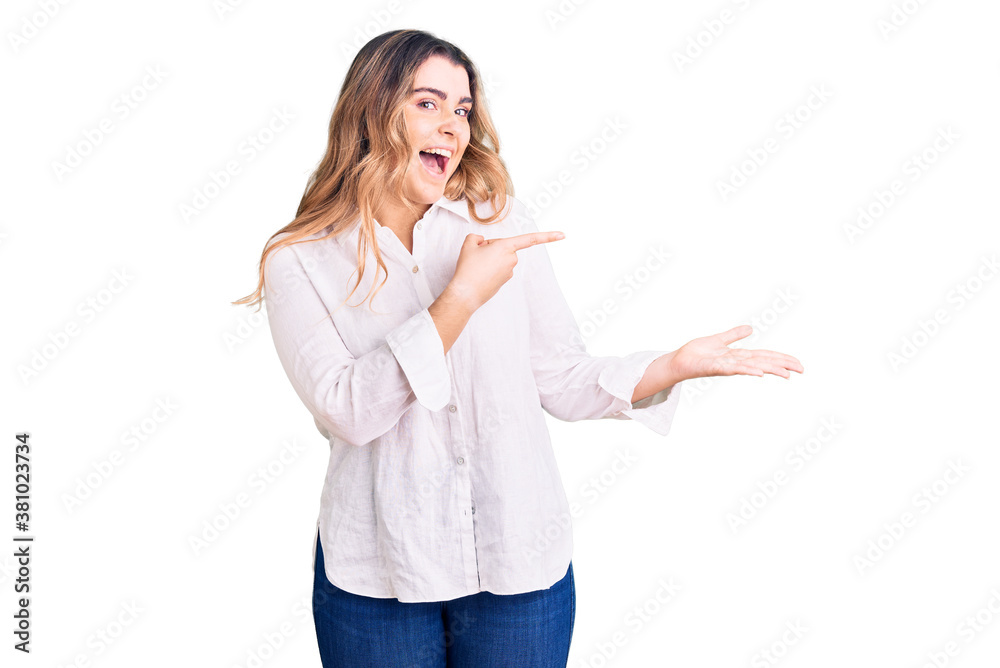 Young caucasian woman wearing casual clothes amazed and smiling to the camera while presenting with hand and pointing with finger. Young caucasian woman wearing casual clothes amazed and smiling to the camera while presenting with hand and pointing with finger.