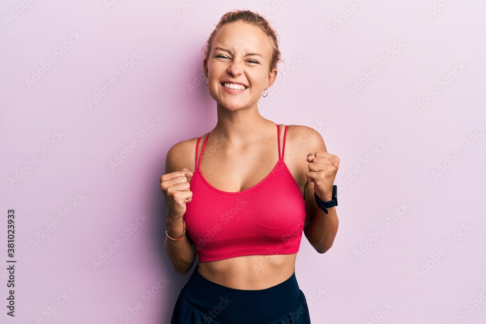 Beautiful caucasian woman wearing sportswear excited for success with arms raised and eyes closed celebrating victory smiling. winner concept. Beautiful caucasian woman wearing sportswear excited for success with arms raised and eyes closed celebrating victory smiling. winner concept.