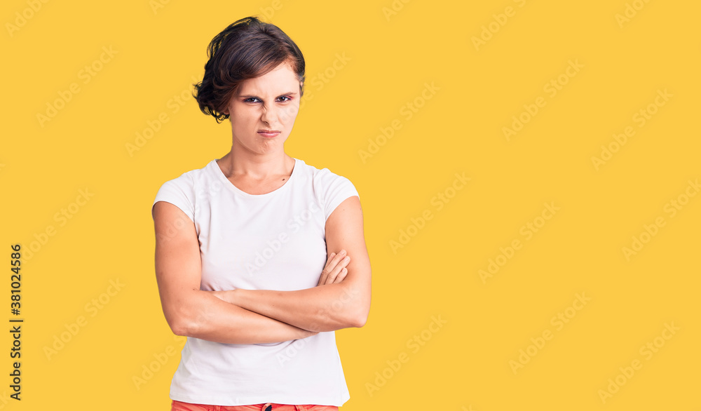 Beautiful young woman with short hair wearing casual clothes skeptic and nervous, disapproving expression on face with crossed arms. negative person. Beautiful young woman with short hair wearing casual clothes skeptic and nervous, disapproving expression on face with crossed arms. negative person.