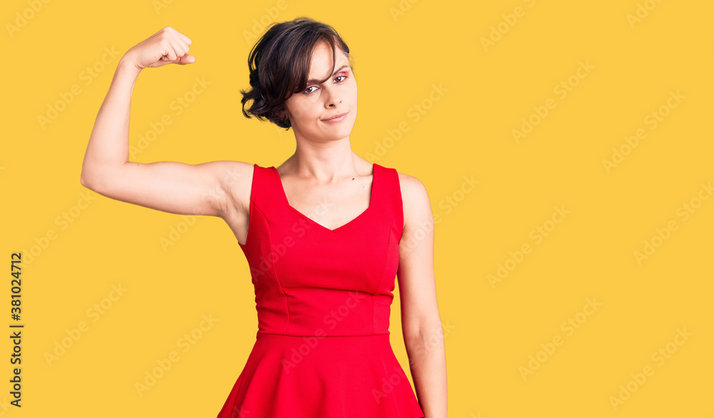 Beautiful young woman with short hair wearing casual style with sleeveless shirt strong person showing arm muscle, confident and proud of power
