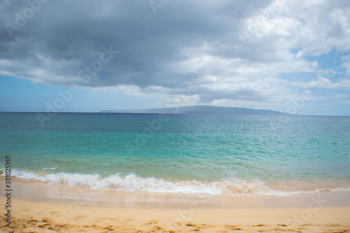 Beach in Hawaii with a dark cloud passing above.