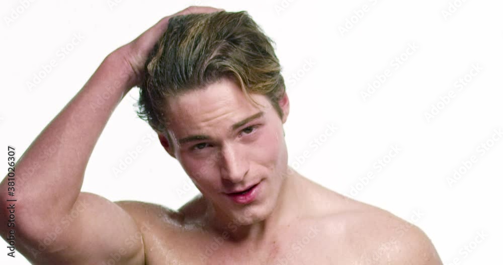 Young male stands under running water and puts his hand through his hair. Young male stands under running water and puts his hand through his hair.