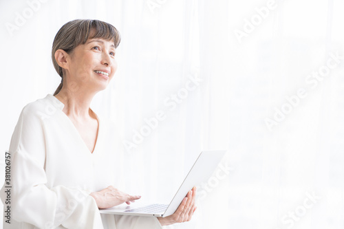部屋でラップトップコンピューターを見るシニア女性