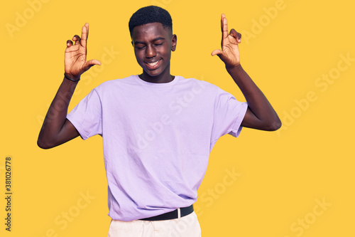 Young african american man wearing casual clothes gesturing finger crossed smiling with hope and eyes closed. luck and superstitious concept.