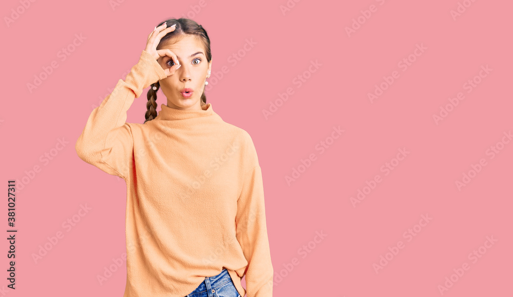 Fototapeta premium Beautiful caucasian woman with blonde hair wearing casual winter sweater doing ok gesture shocked with surprised face, eye looking through fingers. unbelieving expression.