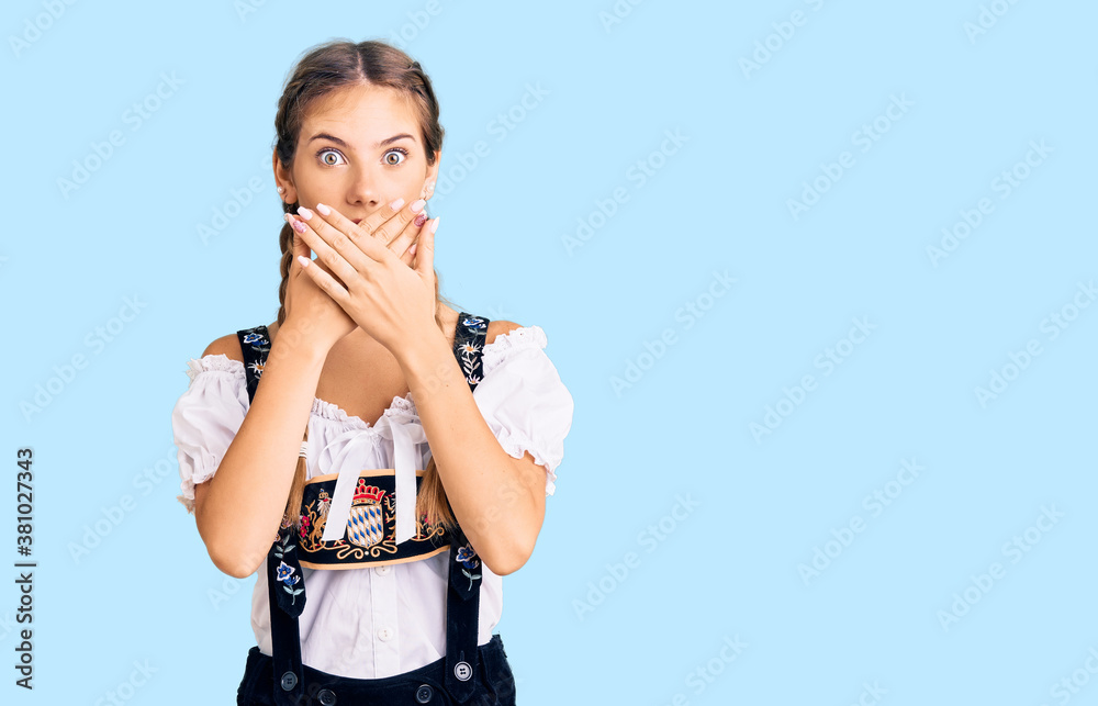 Beautiful caucasian woman with blonde hair wearing octoberfest traditional clothes shocked covering mouth with hands for mistake. secret concept. Beautiful caucasian woman with blonde hair wearing octoberfest traditional clothes shocked covering mouth with hands for mistake. secret concept.