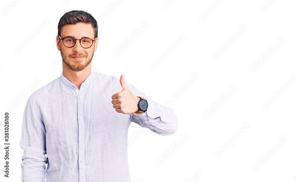 Handsome young man with bear wearing elegant business shirt and glasses doing happy thumbs up gesture with hand. approving expression looking at the camera showing success. Handsome young man with bear wearing elegant business shirt and glasses doing happy thumbs up gesture with hand. approving expression looking at the camera showing success.