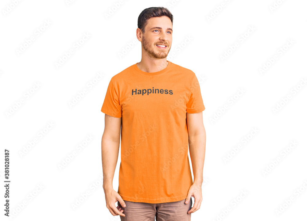 Fototapeta premium Handsome young man with bear wearing tshirt with happiness word message smiling looking to the side and staring away thinking.
