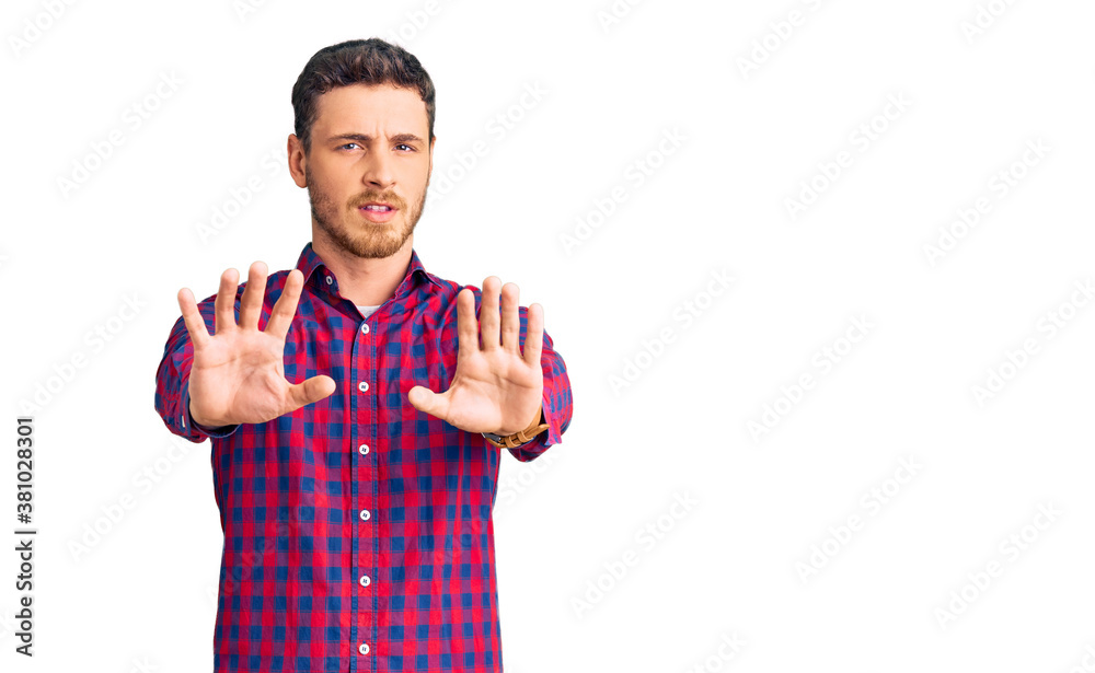 Handsome young man with bear wearing casual shirt doing stop gesture with hands palms, angry and frustration expression Handsome young man with bear wearing casual shirt doing stop gesture with hands palms, angry and frustration expression