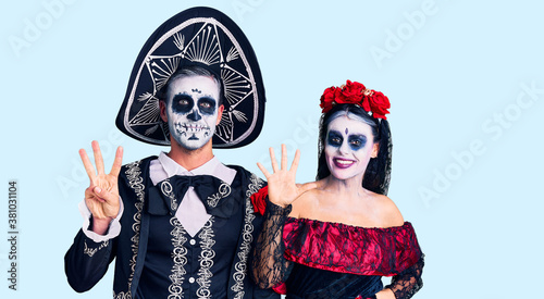 Young couple wearing mexican day of the dead costume over background showing and pointing up with fingers number eight while smiling confident and happy.