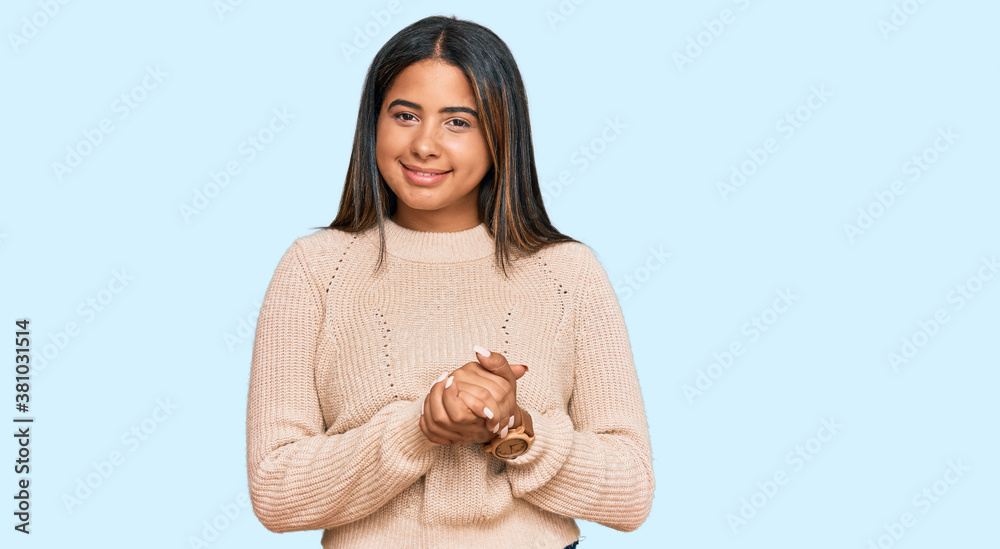Young latin girl wearing wool winter sweater with hands together and crossed fingers smiling relaxed and cheerful. success and optimistic