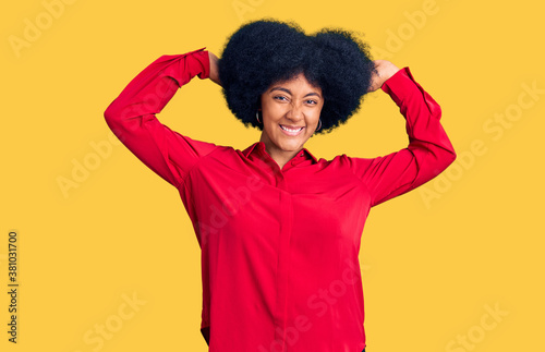 Young african american girl wearing casual clothes relaxing and stretching, arms and hands behind head and neck smiling happy © Krakenimages.com