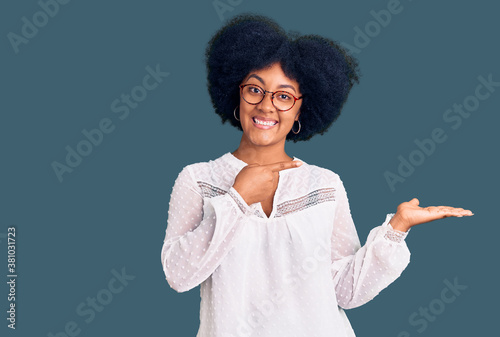 Young african american girl wearing casual clothes amazed and smiling to the camera while presenting with hand and pointing with finger.