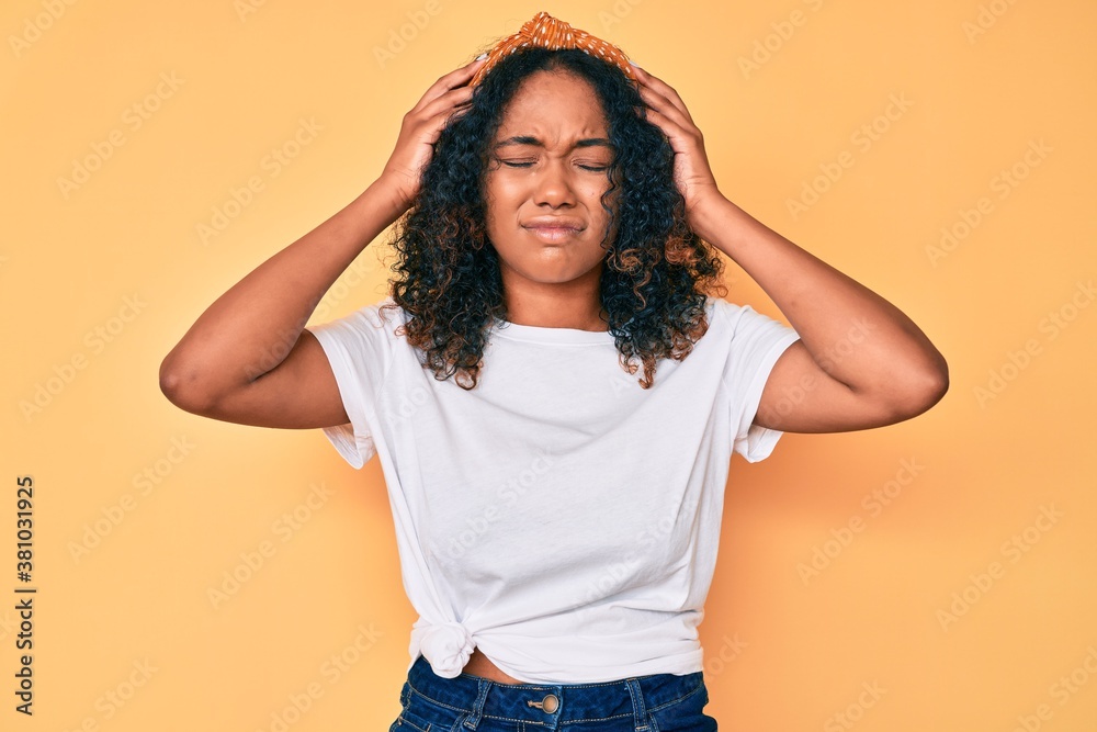 Young african american woman wearing casual clothes suffering from headache desperate and stressed because pain and migraine. hands on head. Young african american woman wearing casual clothes suffering from headache desperate and stressed because pain and migraine. hands on head.