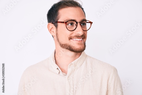 Young handsome man wearing casual clothes and glasses looking away to side with smile on face, natural expression. laughing confident. © Krakenimages.com