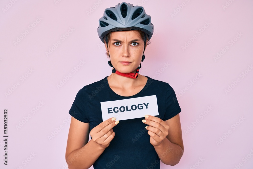 Beautiful caucasian woman wearing bike helmet holding ecology word skeptic and nervous, frowning upset because of problem. negative person. Beautiful caucasian woman wearing bike helmet holding ecology word skeptic and nervous, frowning upset because of problem. negative person.