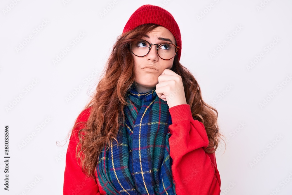 Young beautiful woman wearing casual winter scarf and glasses serious face thinking about question with hand on chin, thoughtful about confusing idea Young beautiful woman wearing casual winter scarf and glasses serious face thinking about question with hand on chin, thoughtful about confusing idea