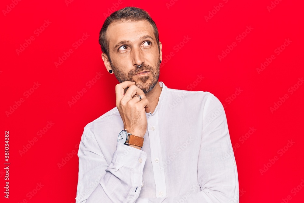 Young handsome man wearing casual clothes thinking concentrated about doubt with finger on chin and looking up wondering Young handsome man wearing casual clothes thinking concentrated about doubt with finger on chin and looking up wondering