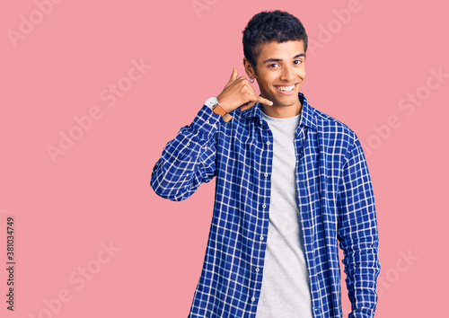 Young african amercian man wearing casual clothes smiling doing phone gesture with hand and fingers like talking on the telephone. communicating concepts.