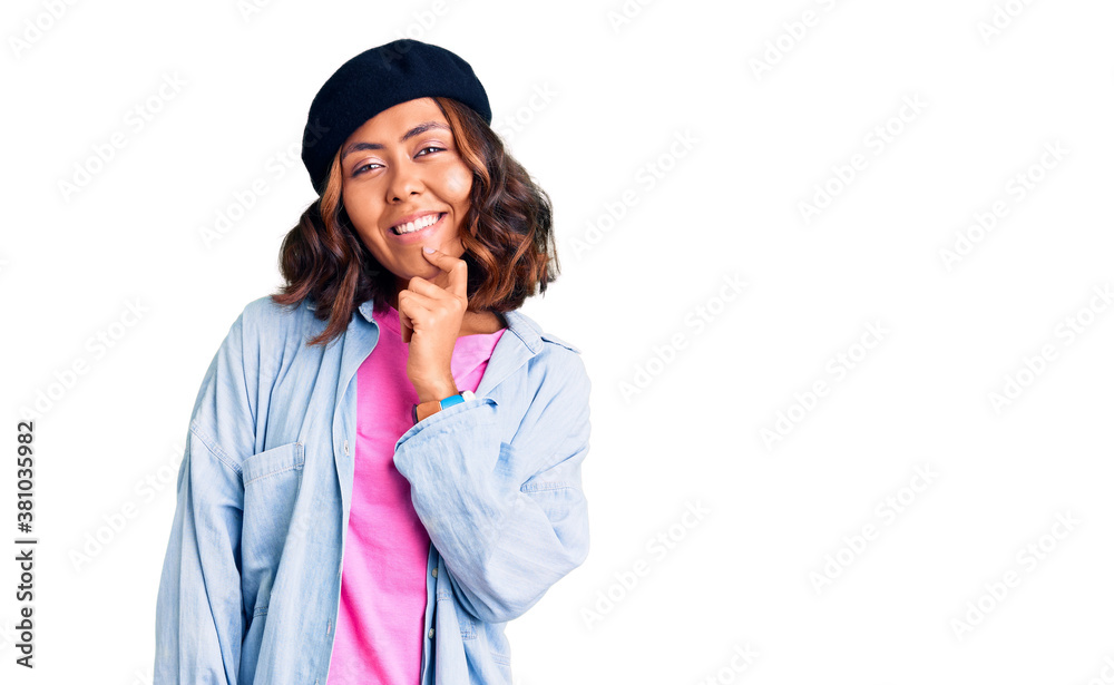 Young beautiful mixed race woman wearing french look with beret looking confident at the camera with smile with crossed arms and hand raised on chin. thinking positive. Young beautiful mixed race woman wearing french look with beret looking confident at the camera with smile with crossed arms and hand raised on chin. thinking positive.