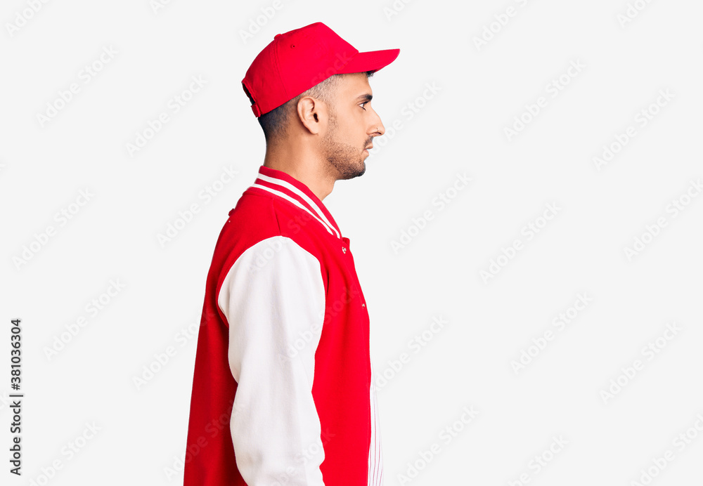 Young hispanic man wearing baseball uniform looking to side, relax profile pose with natural face with confident smile. Young hispanic man wearing baseball uniform looking to side, relax profile pose with natural face with confident smile.
