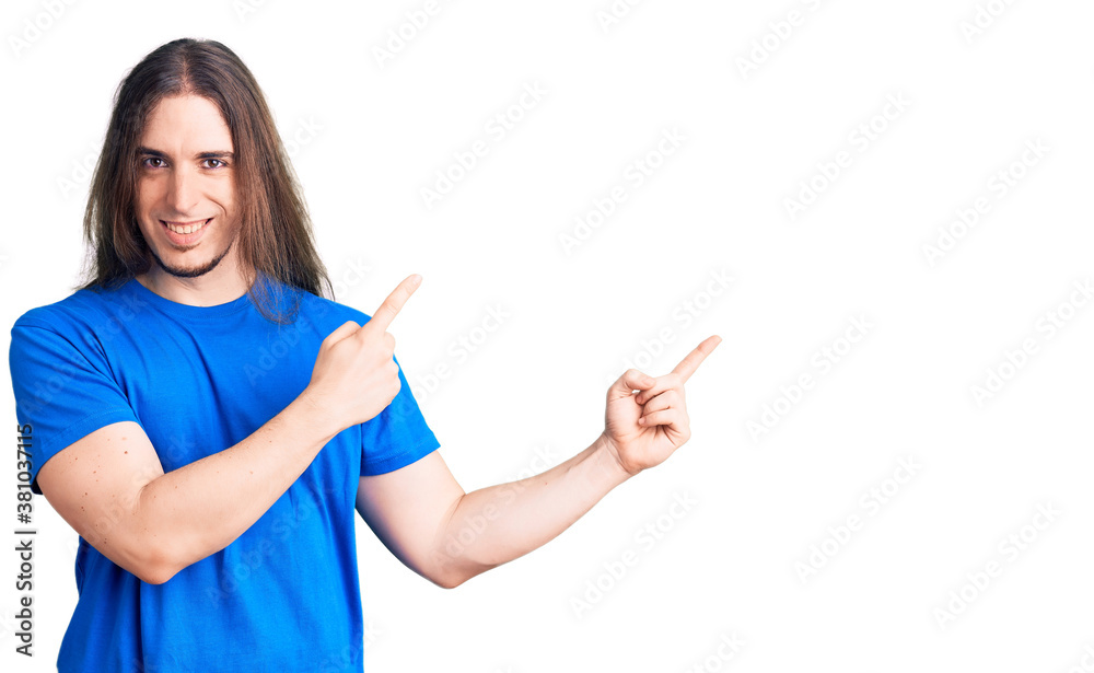 Young adult man with long hair wearing swimwear smiling and looking at the camera pointing with two hands and fingers to the side. Young adult man with long hair wearing swimwear smiling and looking at the camera pointing with two hands and fingers to the side.