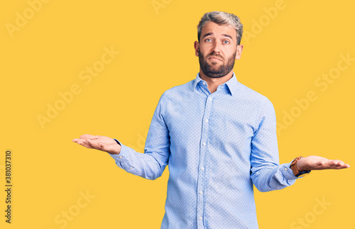 Young handsome blond man wearing elegant shirt clueless and confused with open arms  no idea concept.