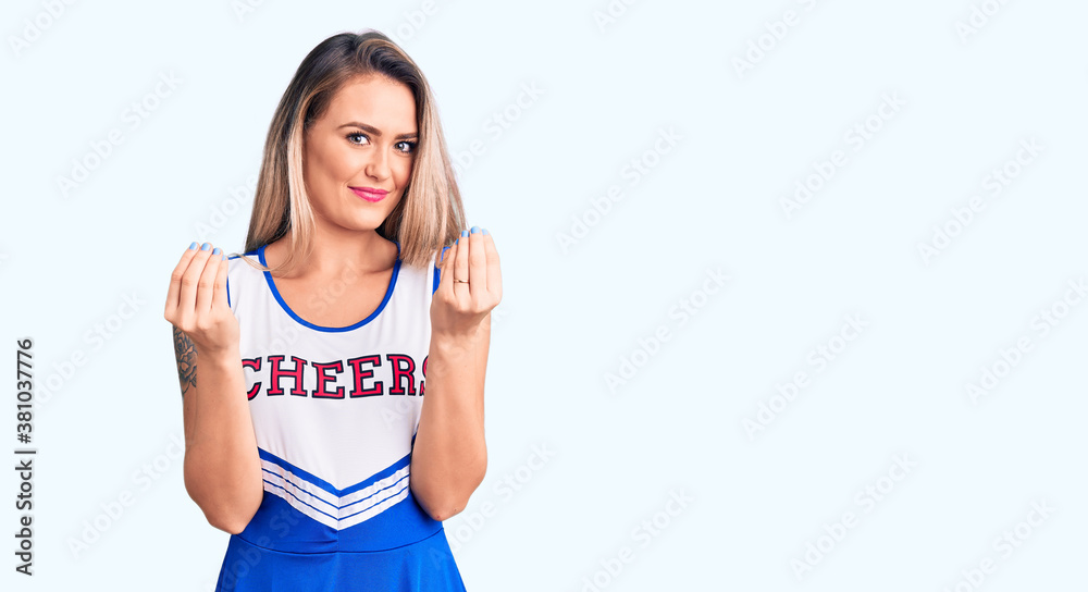 Young beautiful blonde woman wearing cheerleader uniform doing money gesture with hands, asking for salary payment, millionaire business Young beautiful blonde woman wearing cheerleader uniform doing money gesture with hands, asking for salary payment, millionaire business