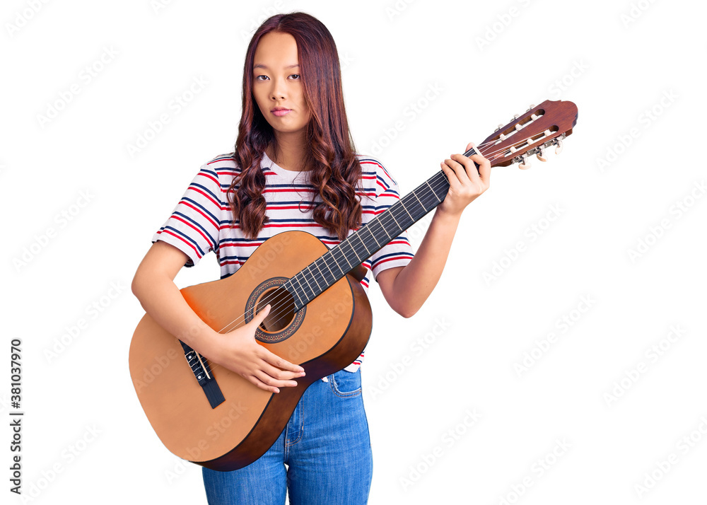 Young beautiful chinese girl playing classical guitar thinking attitude and sober expression looking self confident