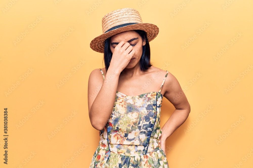 Young beautiful latin woman wearing summer hat tired rubbing nose and eyes feeling fatigue and headache. stress and frustration concept. Young beautiful latin woman wearing summer hat tired rubbing nose and eyes feeling fatigue and headache. stress and frustration concept.
