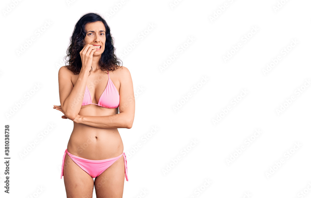 Young beautiful hispanic woman wearing bikini looking stressed and nervous with hands on mouth biting nails. anxiety problem.