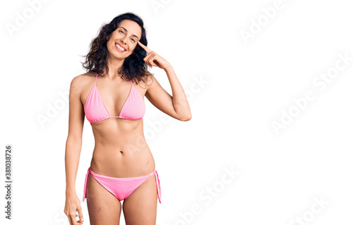 Young beautiful hispanic woman wearing bikini smiling pointing to head with one finger, great idea or thought, good memory © Krakenimages.com