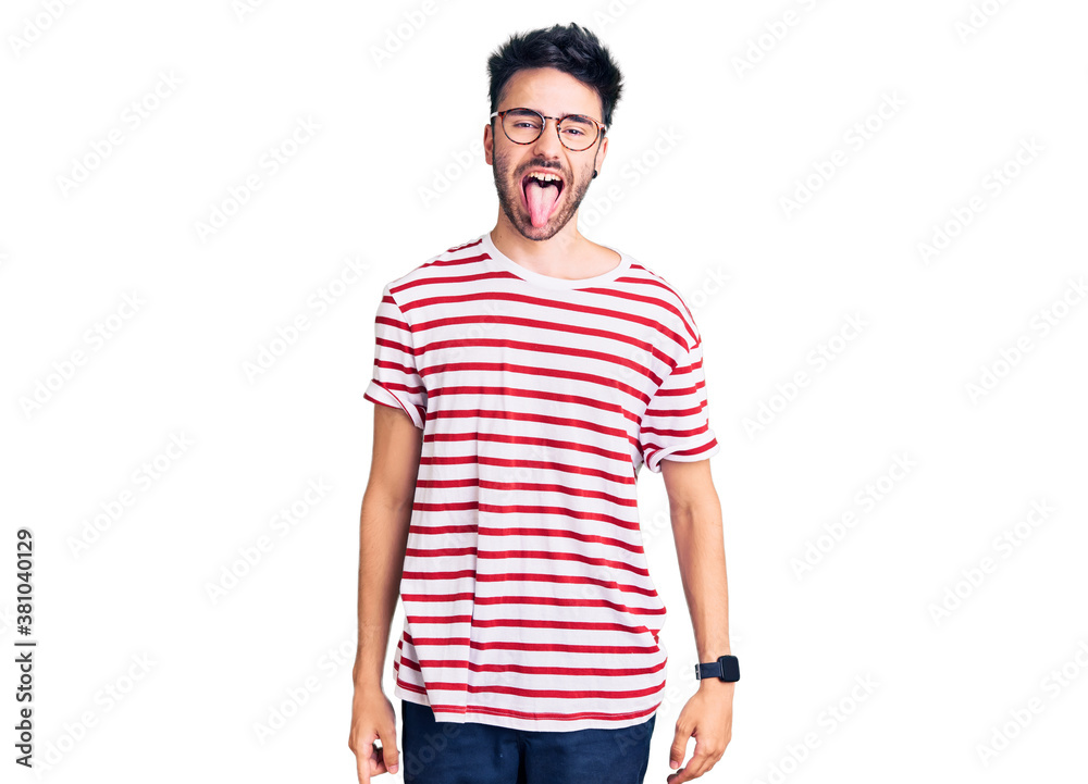 Fototapeta premium Young hispanic man wearing casual clothes sticking tongue out happy with funny expression. emotion concept.