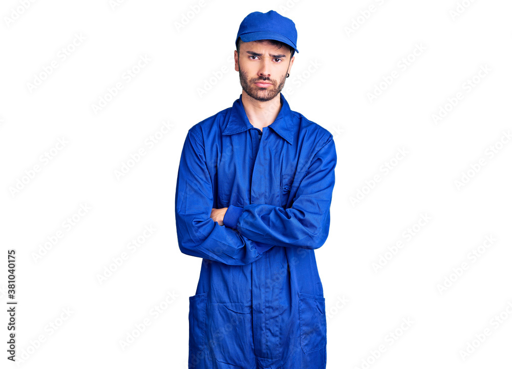 Young hispanic man wearing painter uniform skeptic and nervous, disapproving expression on face with crossed arms. negative person. Young hispanic man wearing painter uniform skeptic and nervous, disapproving expression on face with crossed arms. negative person.