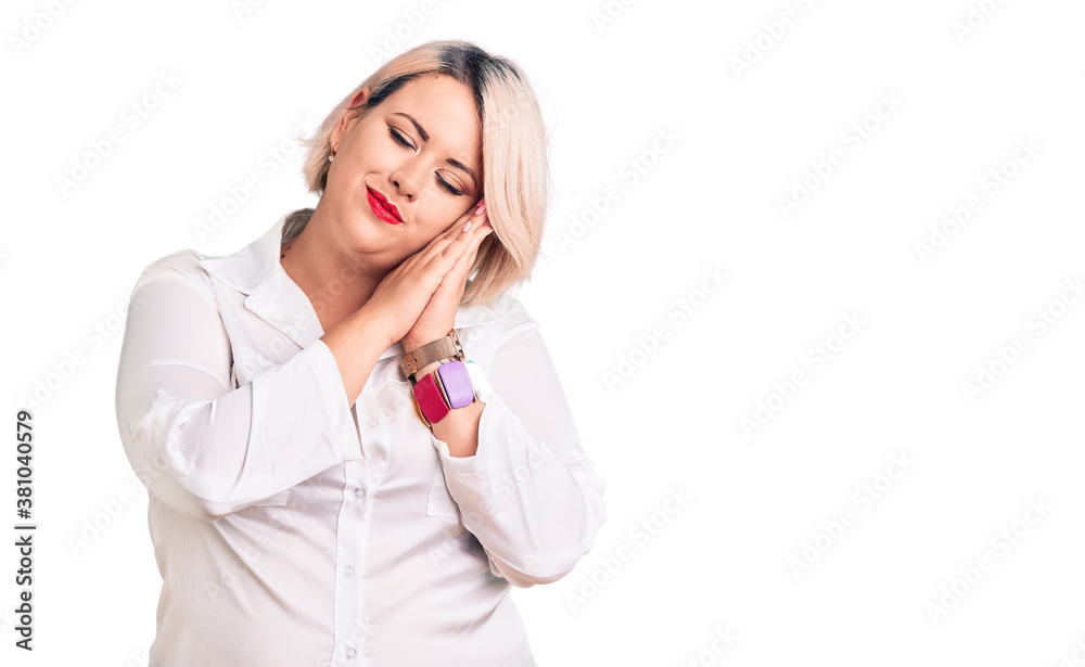 Young blonde plus size woman wearing casual shirt sleeping tired dreaming and posing with hands together while smiling with closed eyes. Young blonde plus size woman wearing casual shirt sleeping tired dreaming and posing with hands together while smiling with closed eyes.