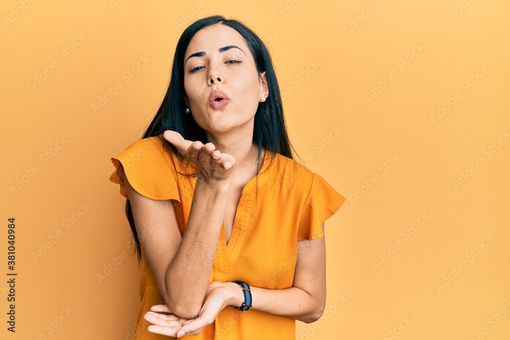 Beautiful young woman wearing casual clothes looking at the camera blowing a kiss with hand on air being lovely and sexy. love expression. Beautiful young woman wearing casual clothes looking at the camera blowing a kiss with hand on air being lovely and sexy. love expression.