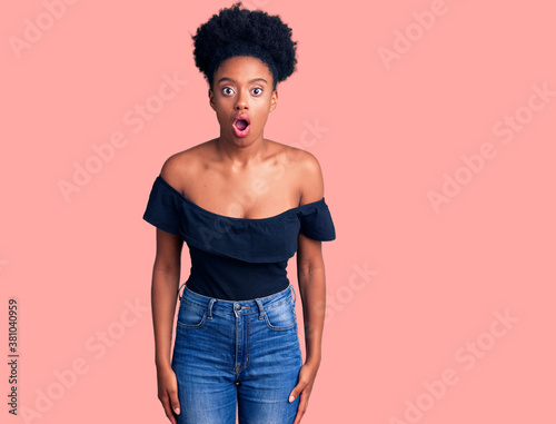 Schilderij op canvas Young african american woman wearing casual clothes scared and amazed with open